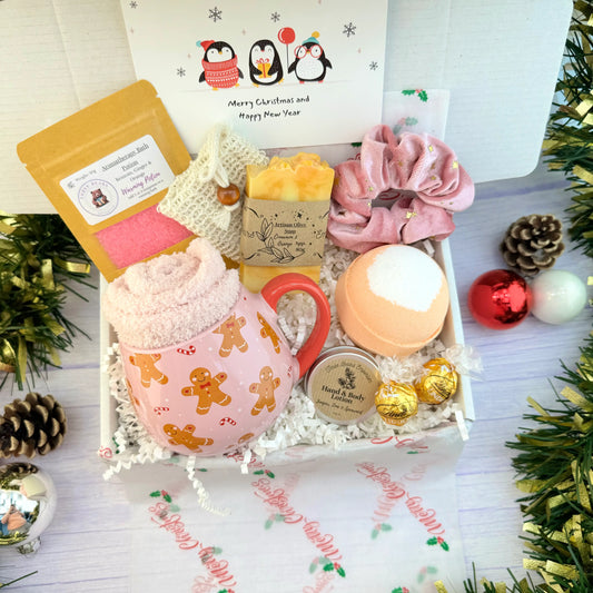 Festive Cheer gift set featuring a gingerbread mug with cosy socks, christmas bath bomb, chocolate truffles, festive hair scrunchie, orange soap, juniper hand lotion and warming bath salts. 